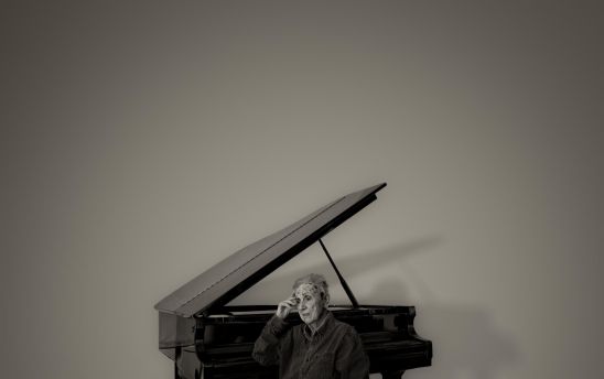 An old woman sitting by a grand piano